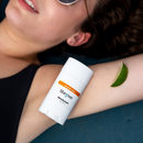 Person applying Tibi River deodorant stick to their arm with a lime wedge nearby.