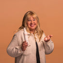 Woman holding a bottle and a small container against a brown background