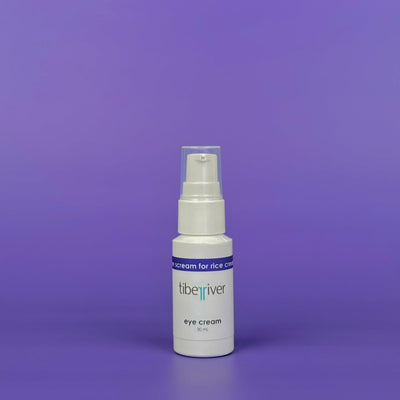 White bottle of eye cream with a blue label on a purple background
