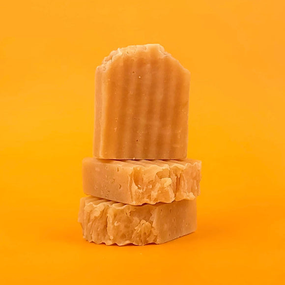 Three bars of brown soap stacked on an orange background