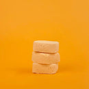 Stack of three beige soap bars on a yellow background