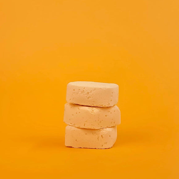 Stack of three beige soap bars on a yellow background